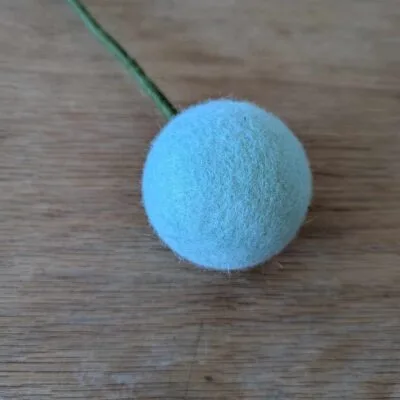 fleur boule en feutre XL eucalyptus de Gry & Sif sur fond en bois