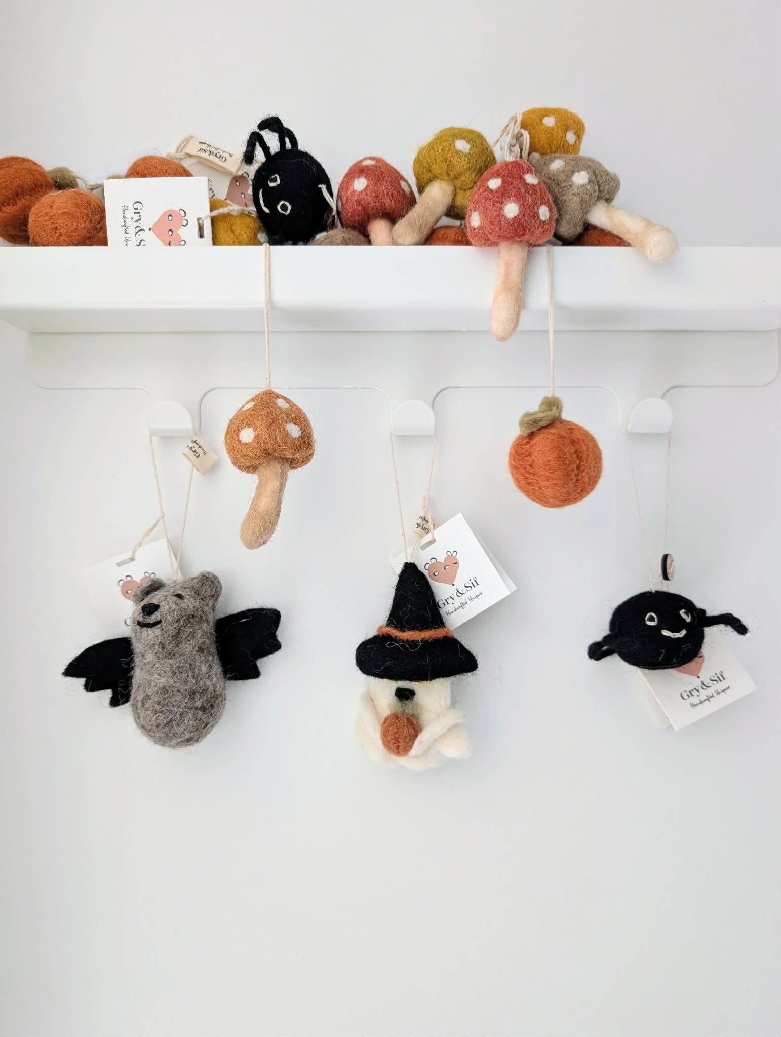 Chauve-souris grise, fantôme d'Halloween et araignée en feutre Gry & Sif suspendus sous une étagère de champignons et de citrouilles
