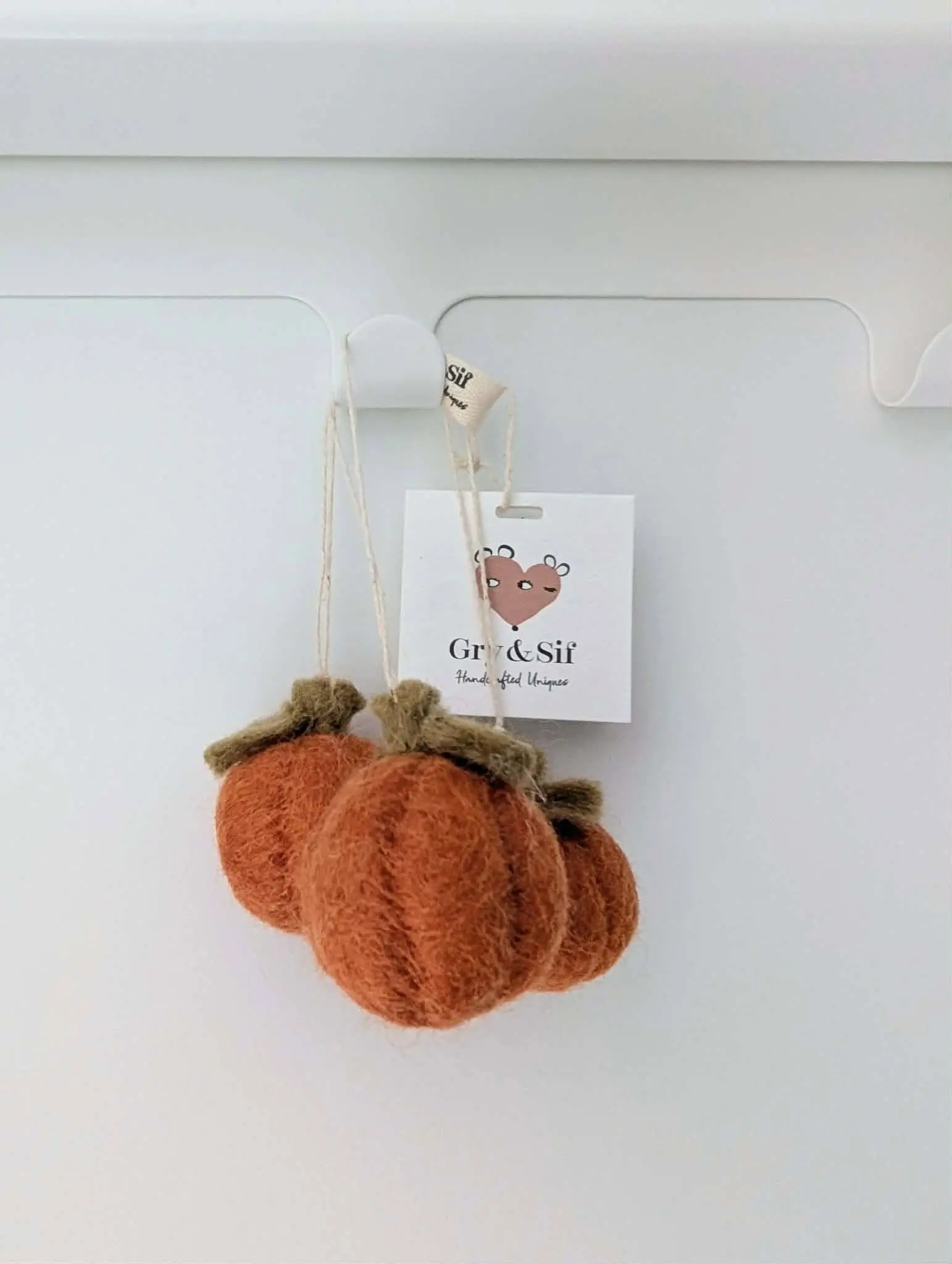 Trois mini citrouilles en feutre orange Gry & Sif suspendues à un crochet avec leur étiquette