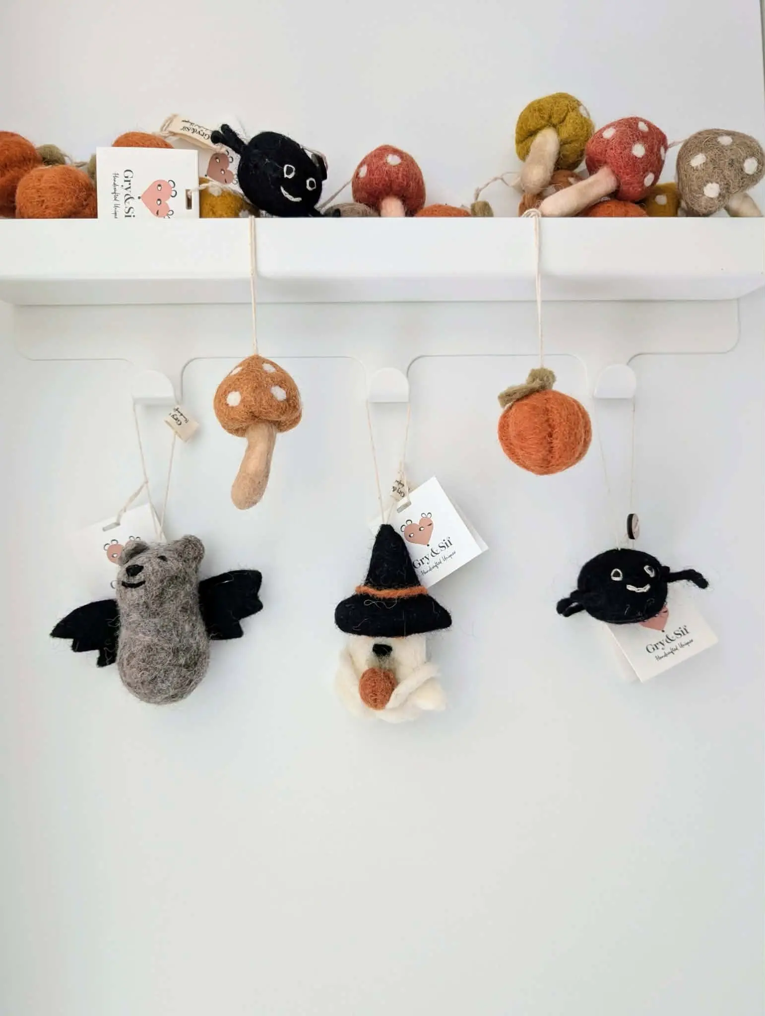 Citrouille, champignon, chauve-souris, fantôme et araignée en feutre Gry & Sif suspendus sous une étagère blanche