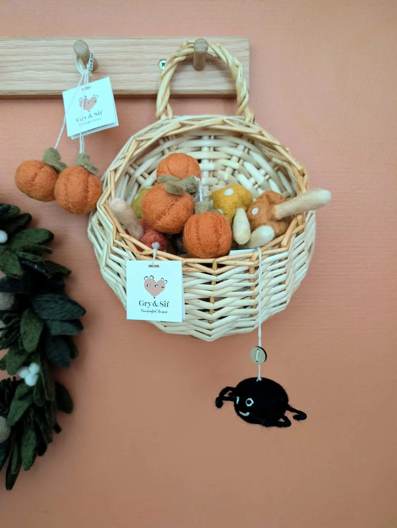 Panier en osier garni de citrouilles et de champignons en feutre Gry & Sif, avec deux citrouilles suspendues à côté